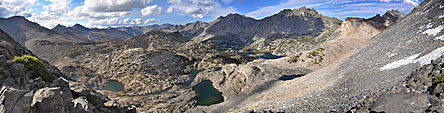 First glimpse north at the Rae Lakes basin from atop Glen Pass. The John Muir Trail wraps around the tree-lined lakes at the upper right and continues north